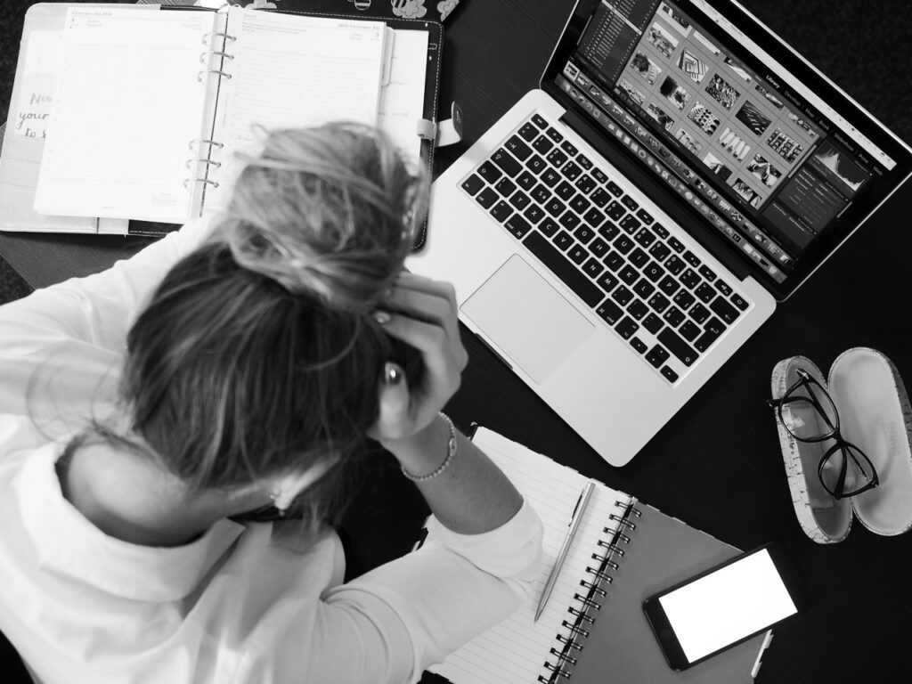Frau sitzt vor Kalender und Laptop und ist verzweifelt